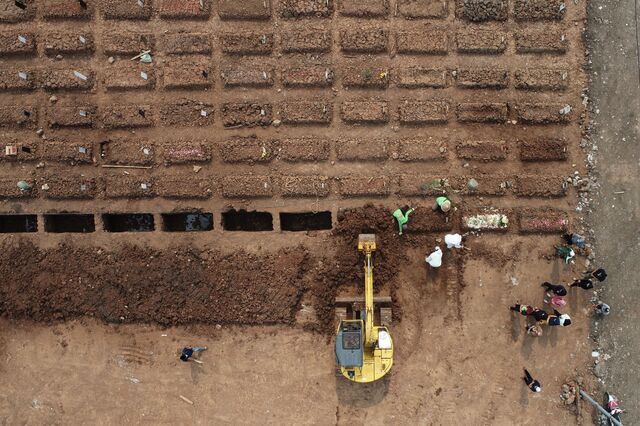 Family and friends observe as workers use an excavator to fill the grave of a Covid-19 victim at the Rorotan cemetery in Jakarta, Indonesia, on Wednesday, Aug. 18, 2021. Indonesia will aim for self-sufficiency in food and vaccines as the government looks to get a hold on the Covid-19 wave battering the nation, President Joko Widodo said Aug. 16.
