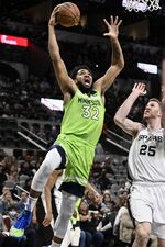 Minnesota Timberwolves' Karl-Anthony Towns (32) shoots against San Antonio Spurs' Jakob Poeltl during the first half of an NBA basketball game on Monday, March 14, 2022, in San Antonio. (AP Photo/Darren Abate)