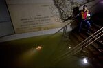 A man shines a flashlight on standing water inside the South Ferry 1 subway station in New York, in the wake of Superstorm Sandy.