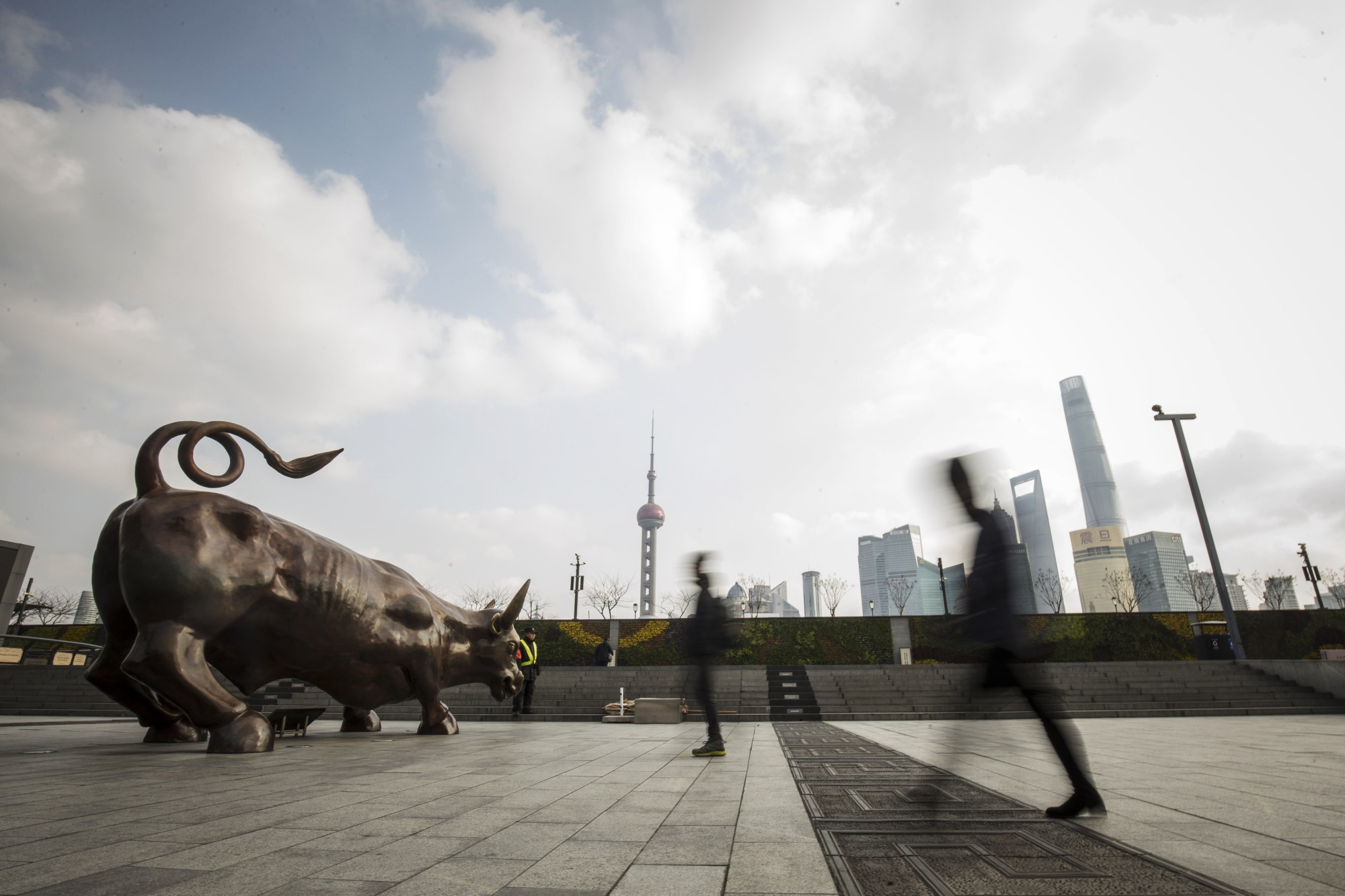 Pedestrians walk past the Bund Bull statue&nbsp;in Shanghai.