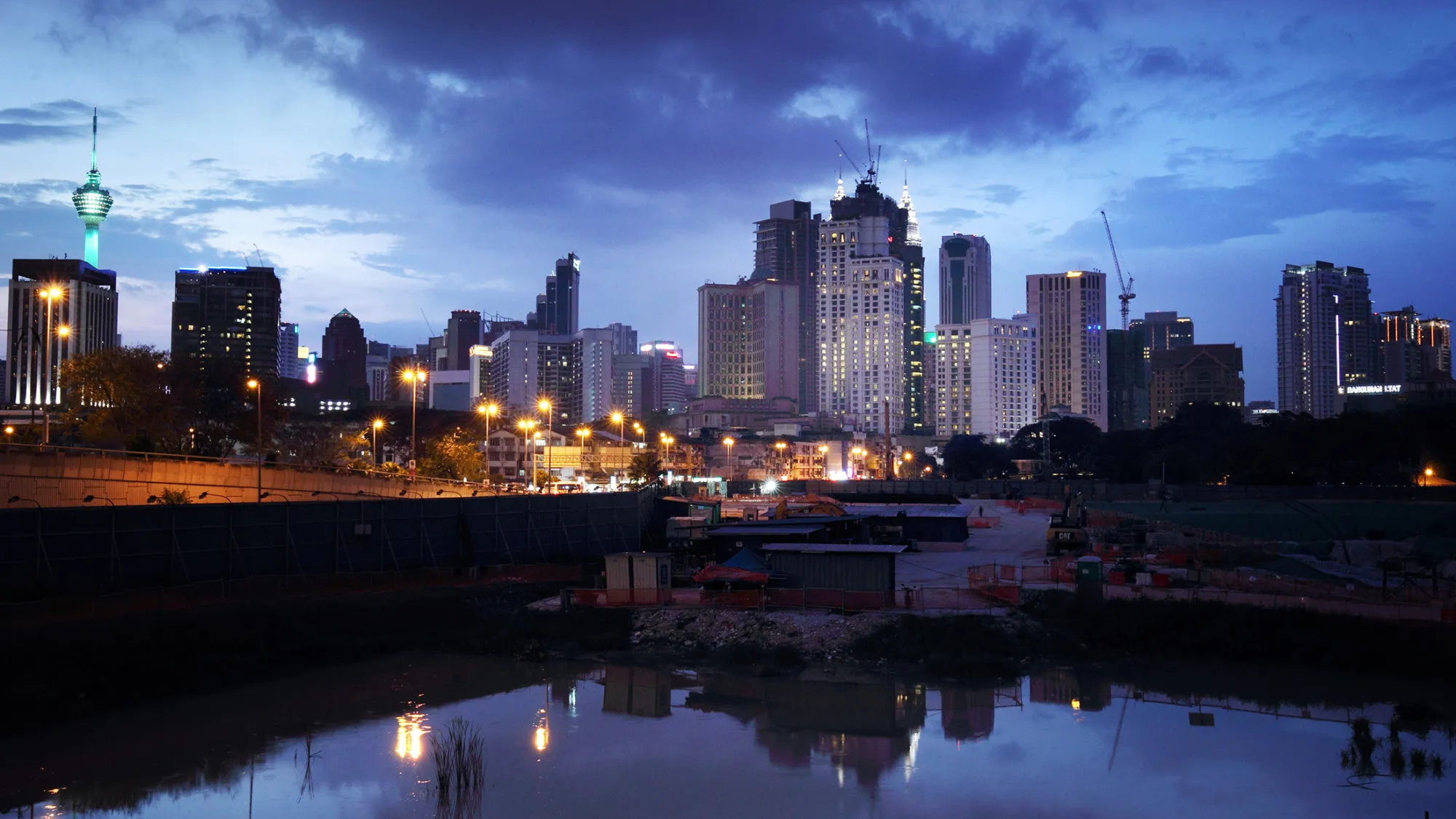 The Tun Razak Exchange (TRX) project, developed by 1Malaysia Development Bhd. (1MDB), foreground, stands under construction as buildings stand illuminated in the distance at dusk in Kuala Lumpur, Malaysia, on Friday, July 17, 2015. As Malaysia Prime Minister Najib Razak faces an investigation sparked by a Wall Street Journal report that $700 million may have wended its way into his personal bank accounts, the ruling coalition has swiftly closed ranks around him. The probe has sparked a raid on the state investment company 1MDB whose advisory board Najib chairs, and spurred calls to resign from opposition lawmakers.

