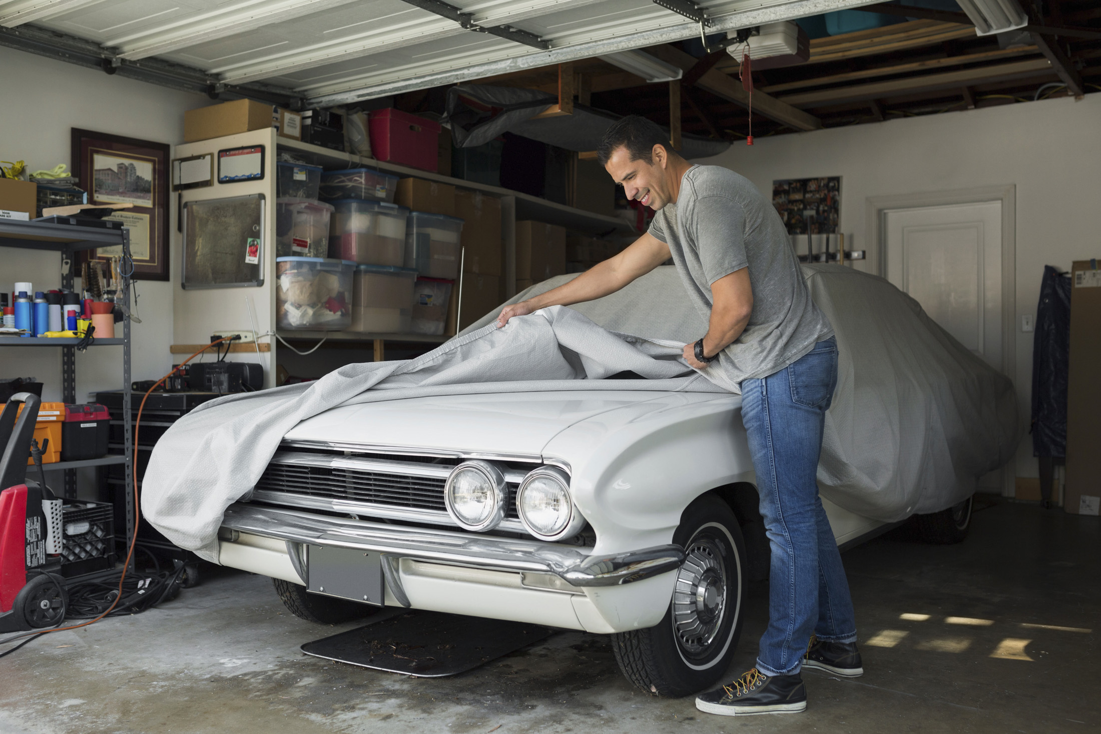 Man uncovering vintage car in garage