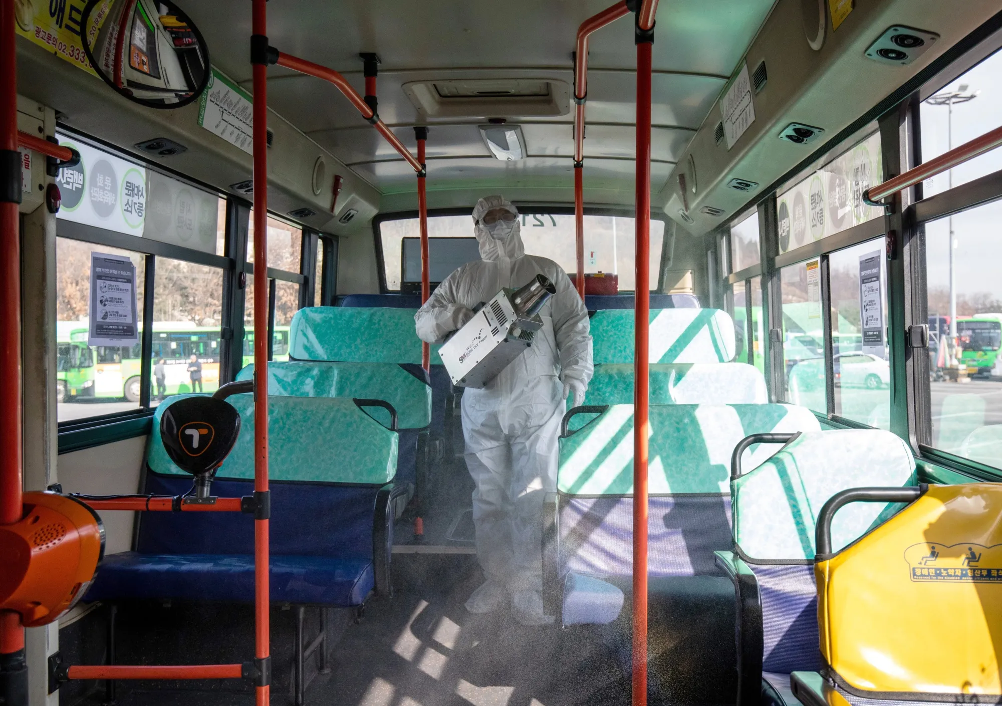 A worker wearing a protective suit sprays disinfectant inside a bus at a depot in the Eunpyeong district of Seoul on Feb. 24.