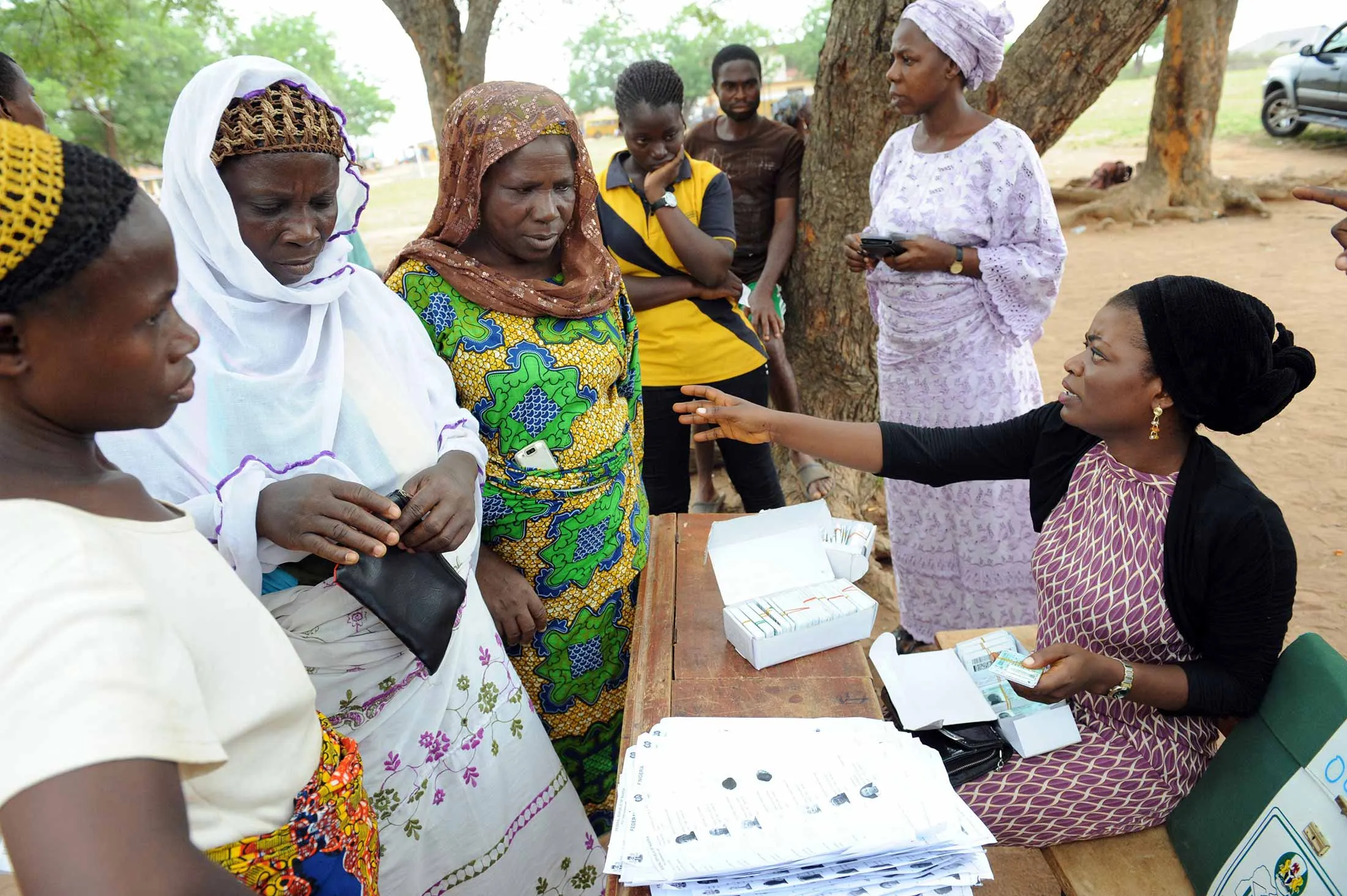 Women wait to collect their Permanent Voter Cards from an official of the Independent National Electoral Commission at Shimawa, a rural town in southwestern Nigeria, on March 13, 2015.
