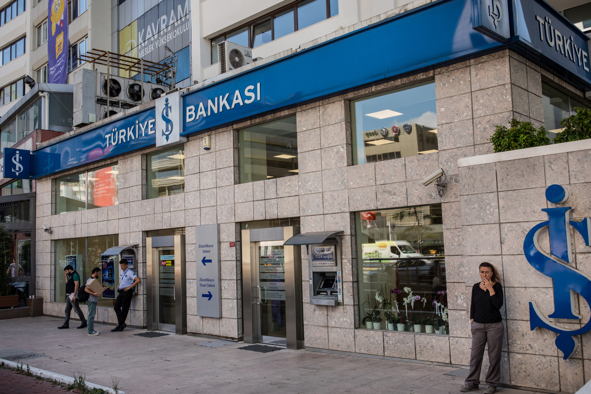 People stand outside a branch of Turkiye Is Bankasi AS, also known as Isbank, in the financial district of Istanbul.