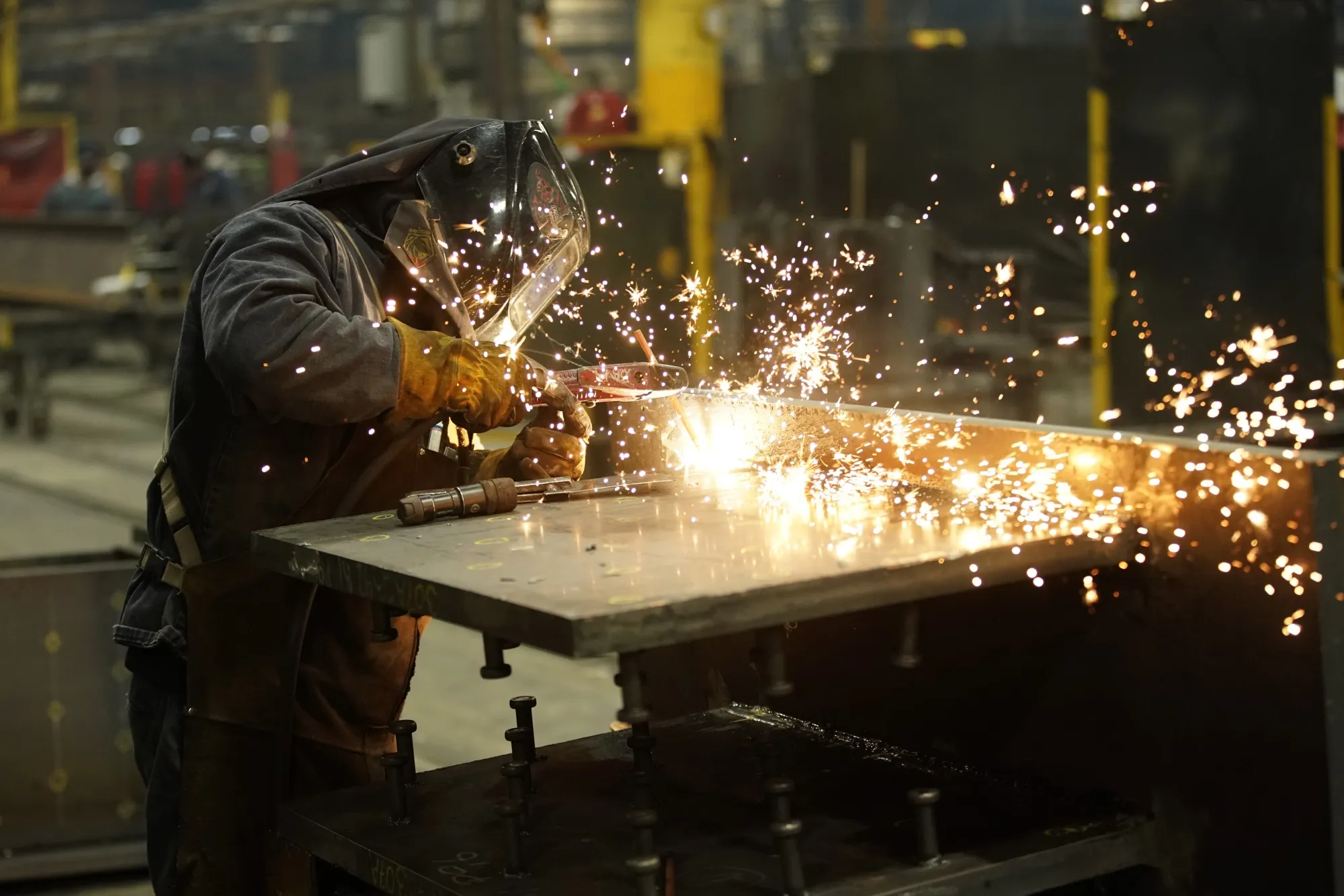 A welder works on&nbsp;a structural steel beam during production at a steel facility in West Jordan, Utah.