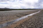 A small stream runs through the dried, cracked earth of a former wetland near Tulelake, Calif., on June 9, 2021.  Southern California's gigantic water supplier has taken the unprecedented step of requiring some 6 million people to cut their outdoor watering to one day a week as drought continues to plague the state. (AP Photo/Nathan Howard, File)