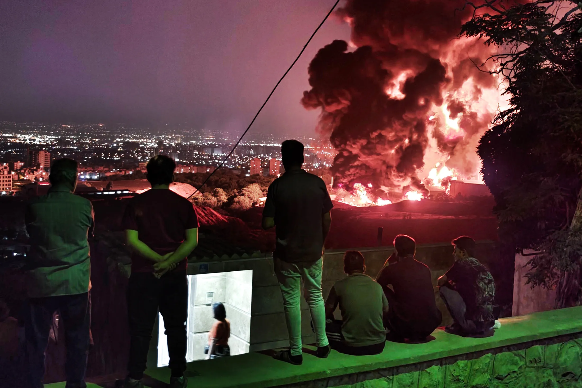 Residents&nbsp;observe fire and smoke from an Israeli attack on the Shahran oil depot in Tehran on June 15.