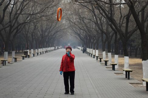 A woman tosses a tube in the air while exercising at Tiantan Park in Beijing.