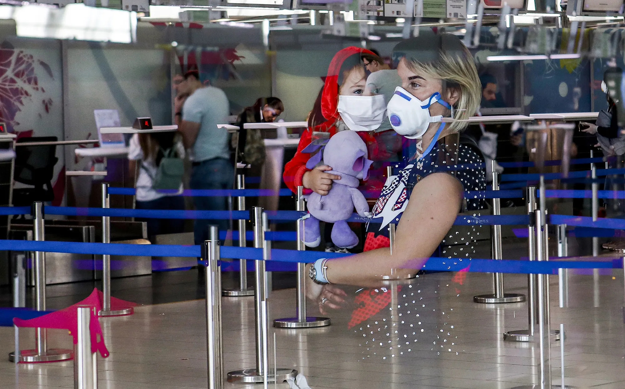 A woman carries a&nbsp;child as they wait at the check-in counters of Larnaca International Airport in Cyprus.&nbsp;