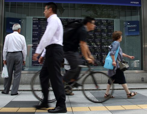 株価ボード前の歩行者