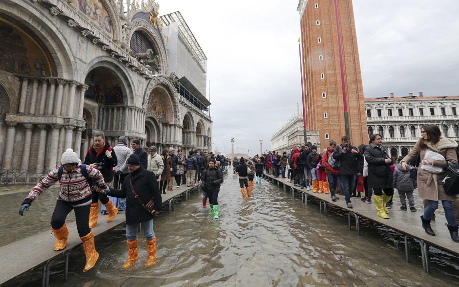 Tourists walk on raised platforms during a period of seasonal high water in Venice in February 2015. 