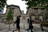 Pedestrians walk past the Bank of Japan (BOJ) headquarters in Tokyo, Japan, on Monday, July 8, 2019. Governor Haruhiko Kuroda said extremely low interest rates will be kept in place until at least around next spring while the bank will keep an eye on risks for price momentum.