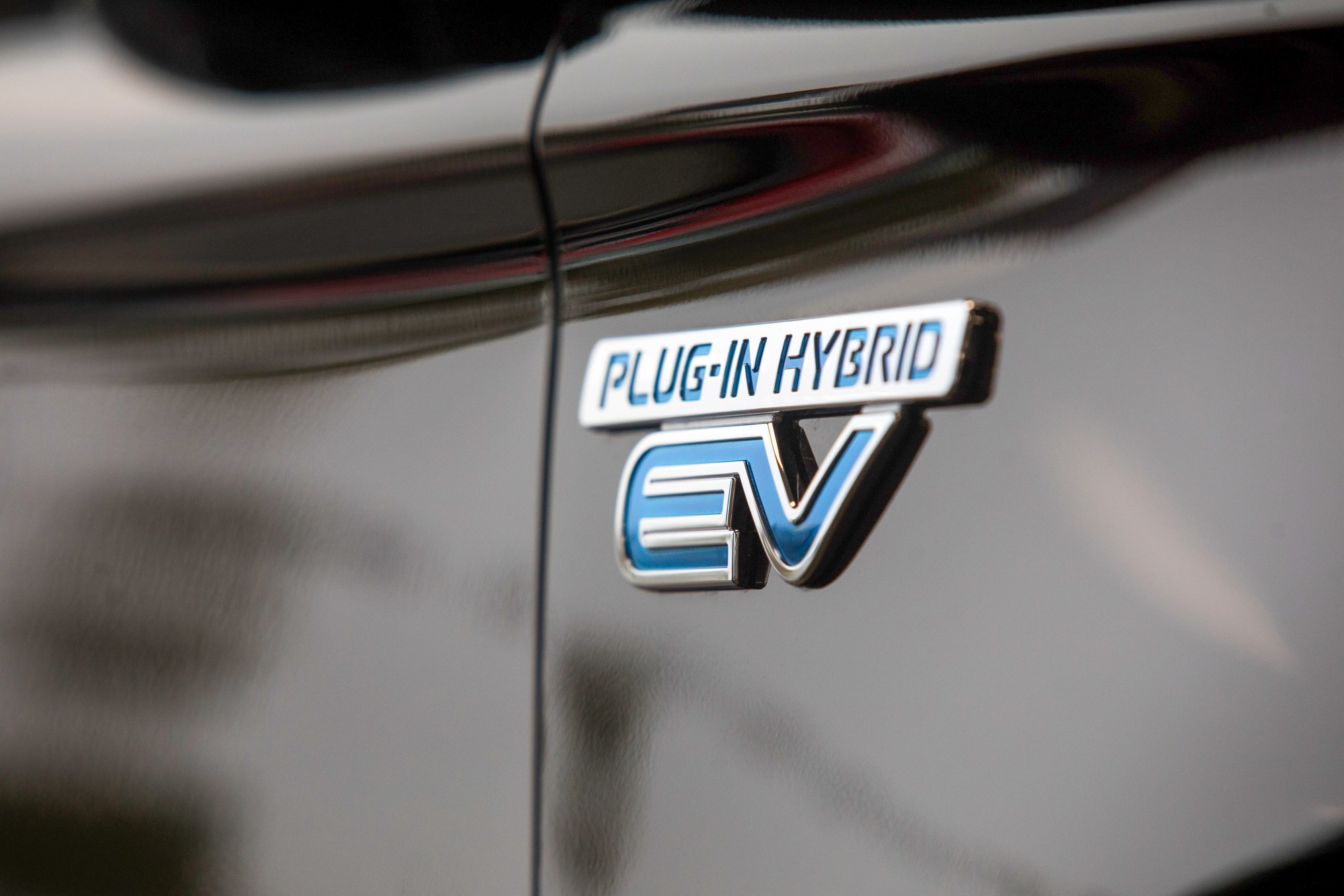 A plug-in hybrid badge on a Mitsubishi Outlander sport utility vehicle.