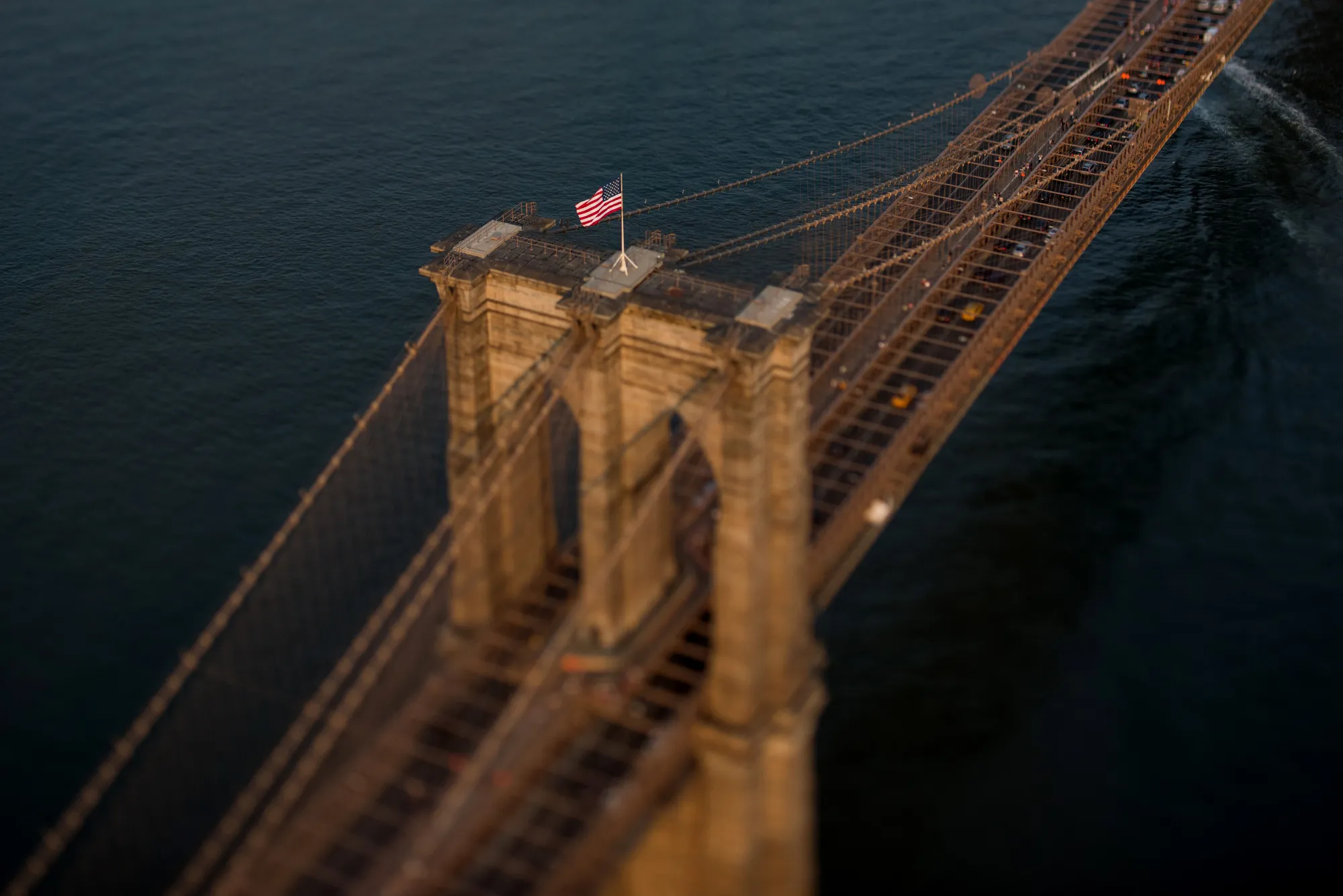 An American flag flies on top of the Brooklyn Bridge in this aerial photograph taken with a tilt-shift lens above New York, U.S.