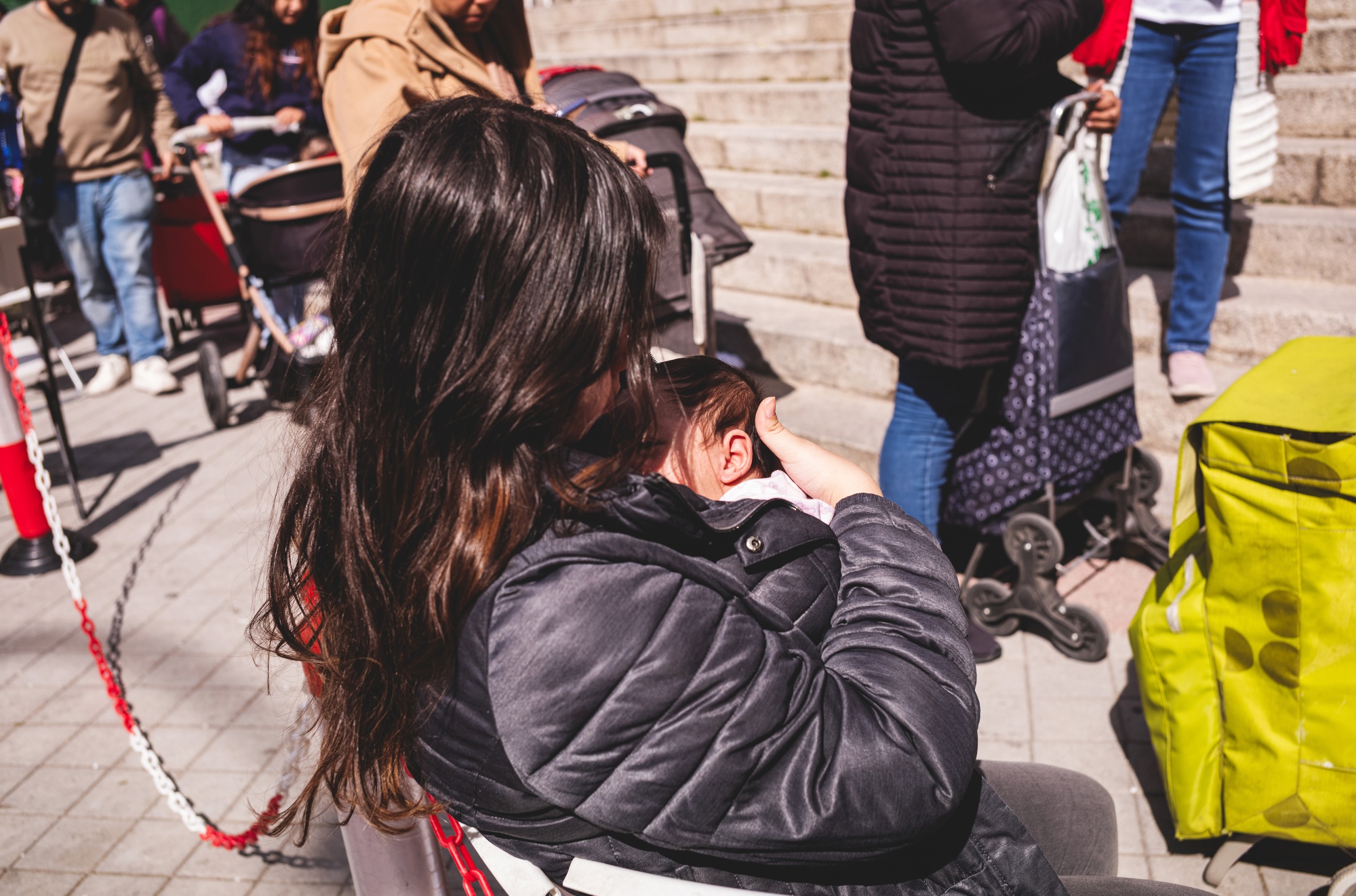 A mother shades her baby while waiting at the Fundacion Madrina in Madrid, Spain, on Thursday, March 19, 2026.