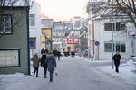 Pedestrians walk along a snow covered street in the shopping district of central Reykjavik, Iceland.
