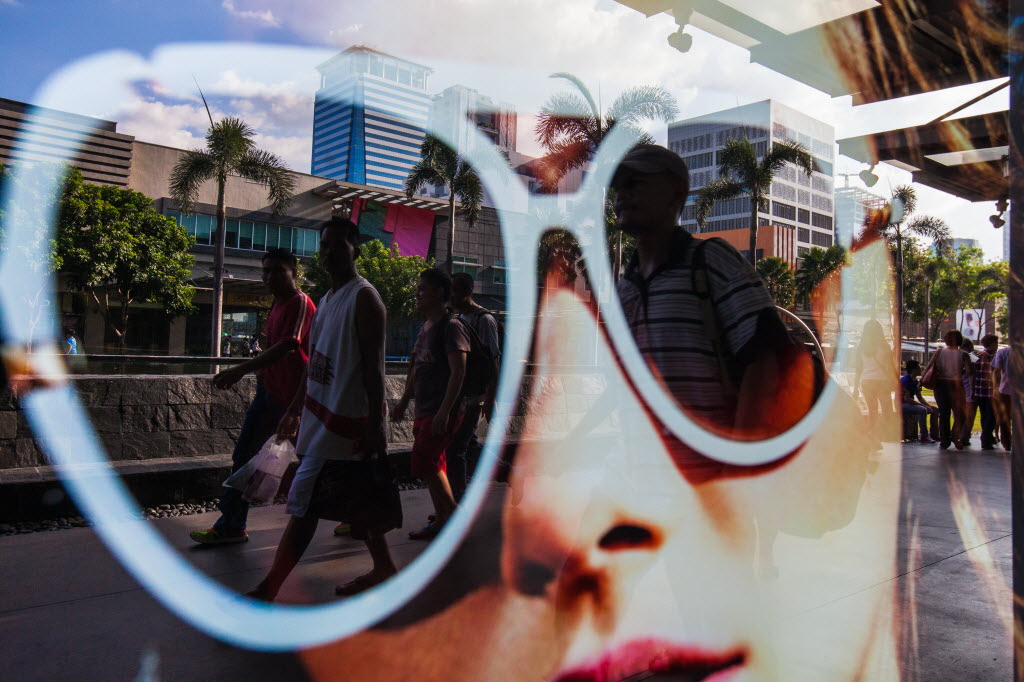 Pedestrians are reflected in a store window display in the Fort Bonifacio district of Manila, the Philippines.
