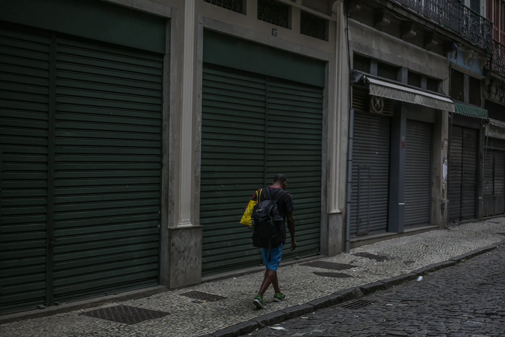 A pedestrian walks by closed stores in downtown Rio de Janeiro on April 16.