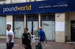 People pass a closed-down pound shop in Chatham, UK.