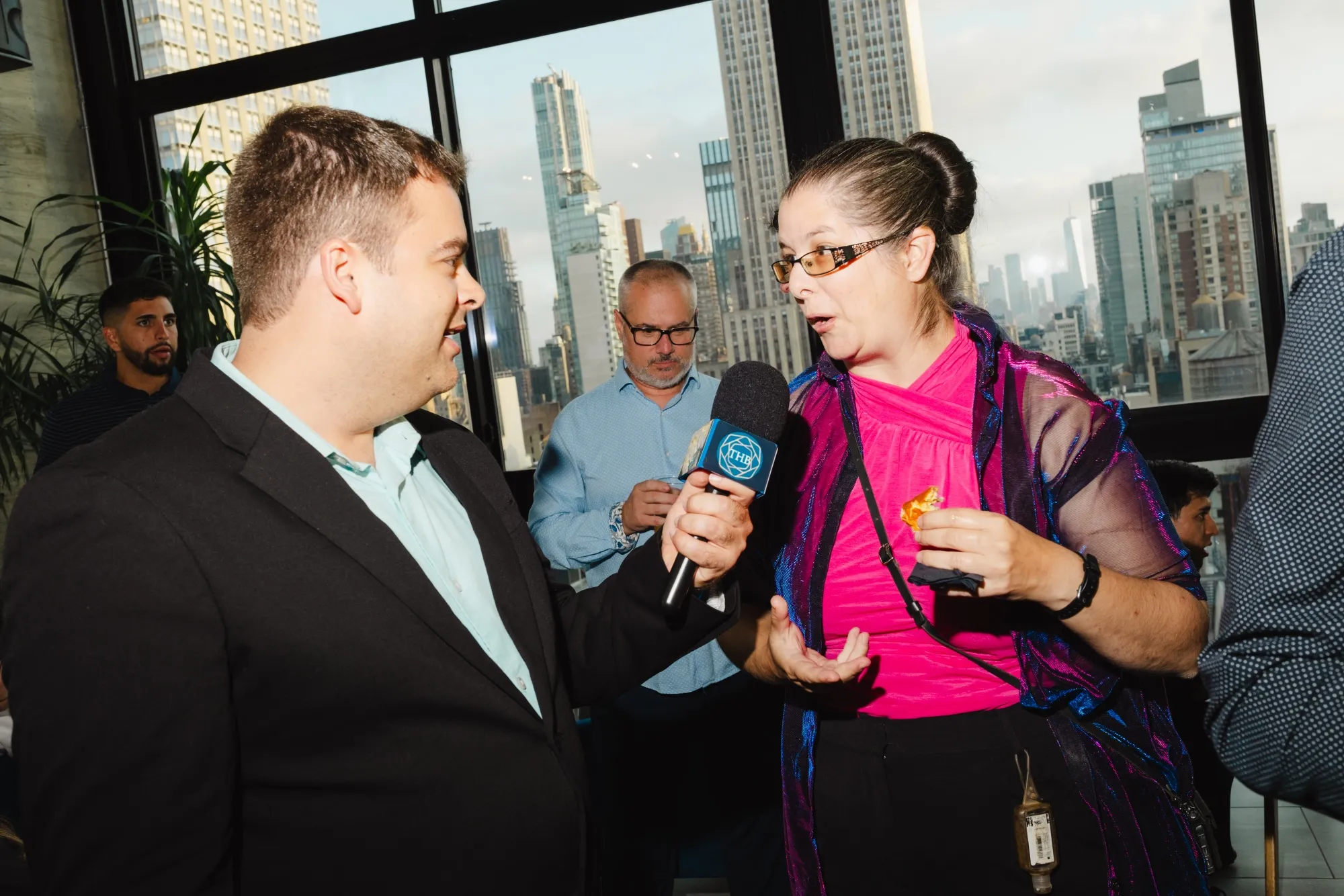 Thomas Bell, a financial influencer holds out a microphone while interviewing another guest of the event.