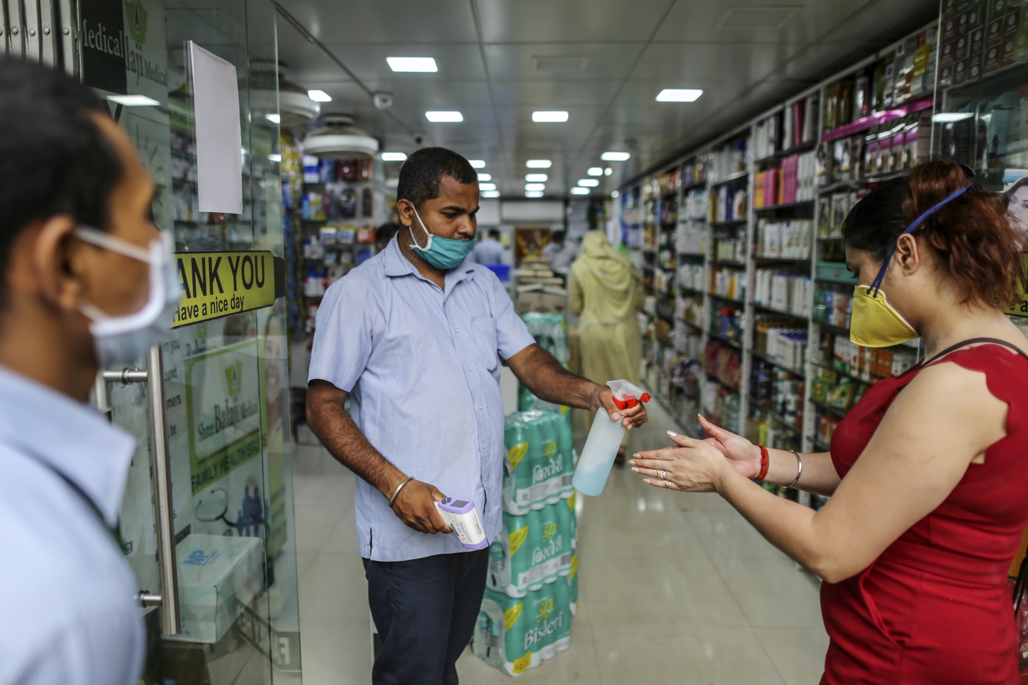 An employee wearing a protective mask sprays a customer's hands with sanitizer&nbsp;in Mumbai, India, on&nbsp;June 1.