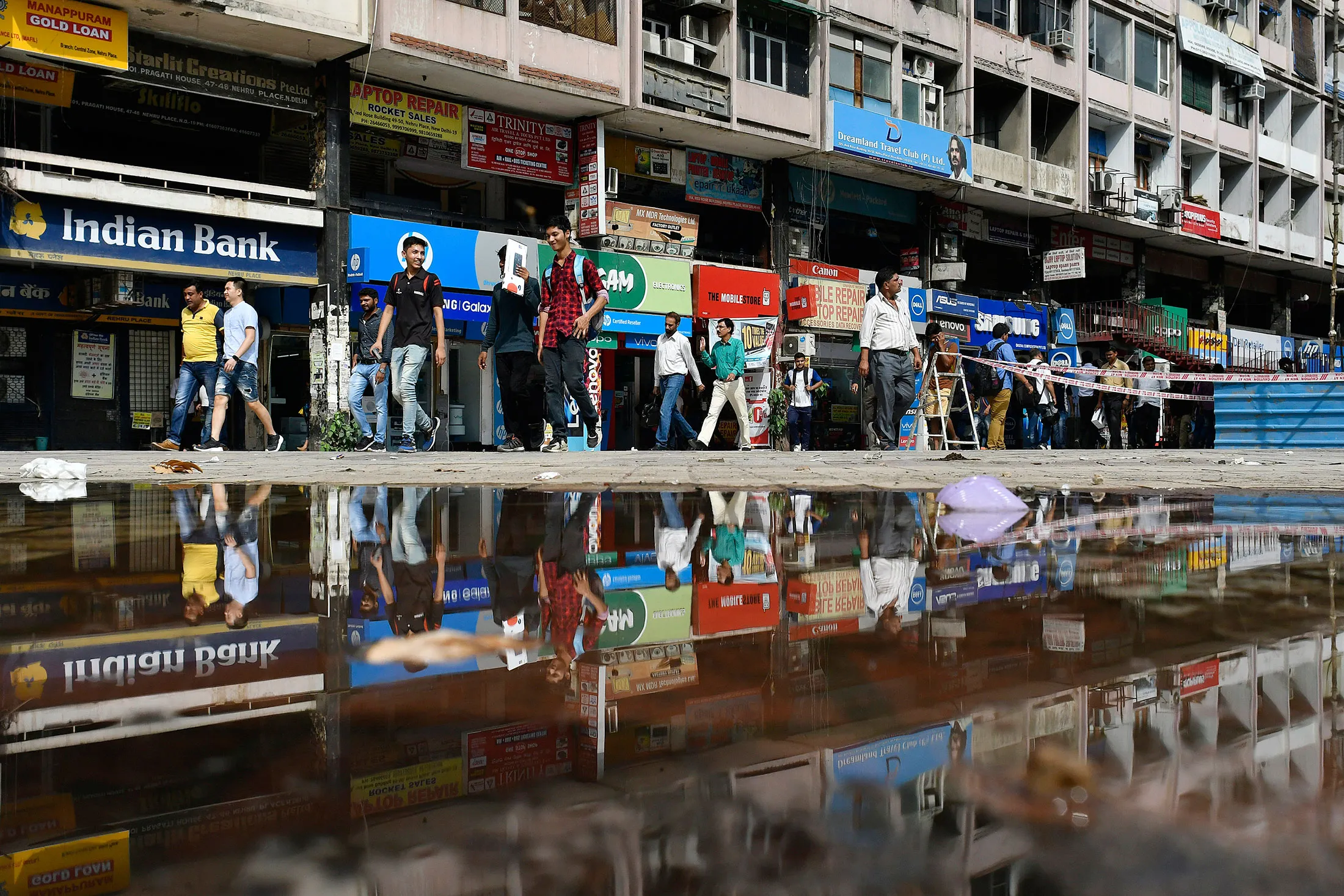 Pedestrians pass by stores in an electronics market at the Delhi-Haryana border in New Delhi, India, on July 1.
