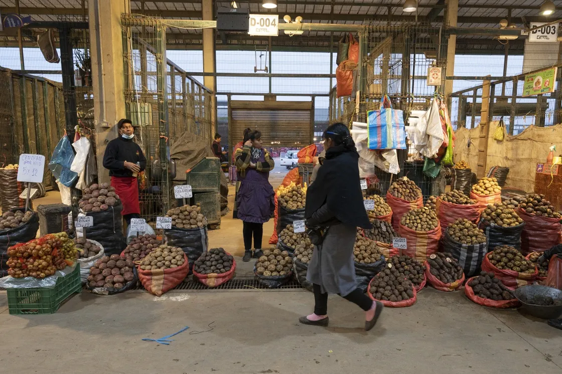 Shoppers walk by potato stands in Lima, Peru.&nbsp;