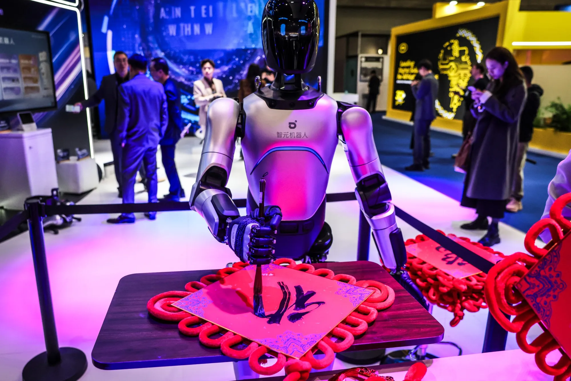 An AgiBot humanoid robot demonstrating calligraphy on the China Telecom Corp. stand at MWC Barcelona 2026.