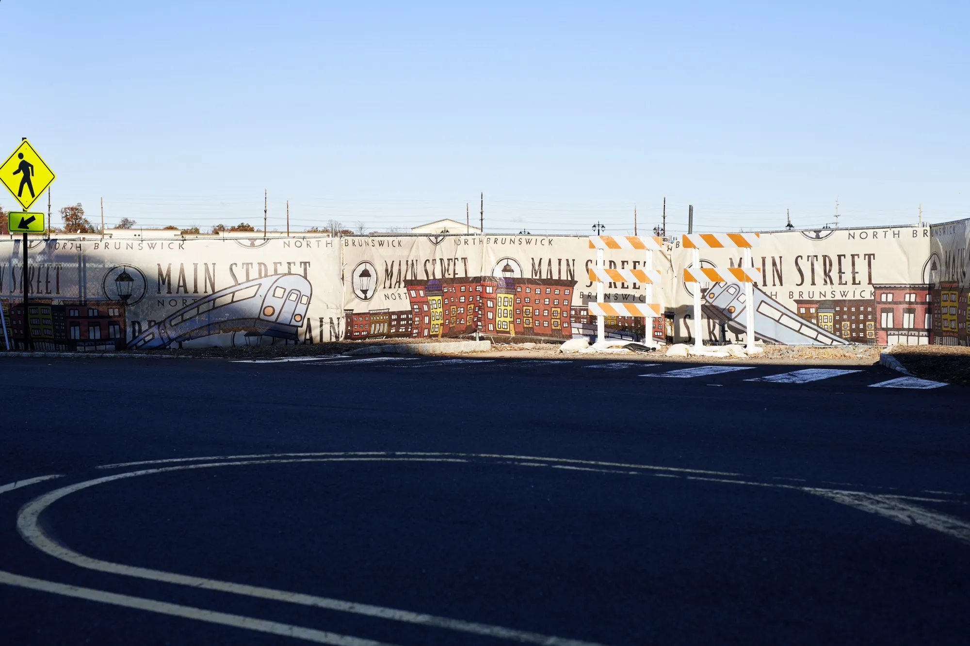 A sign for Main Street North Brunswick includes New Jersey Transit train illustrations.