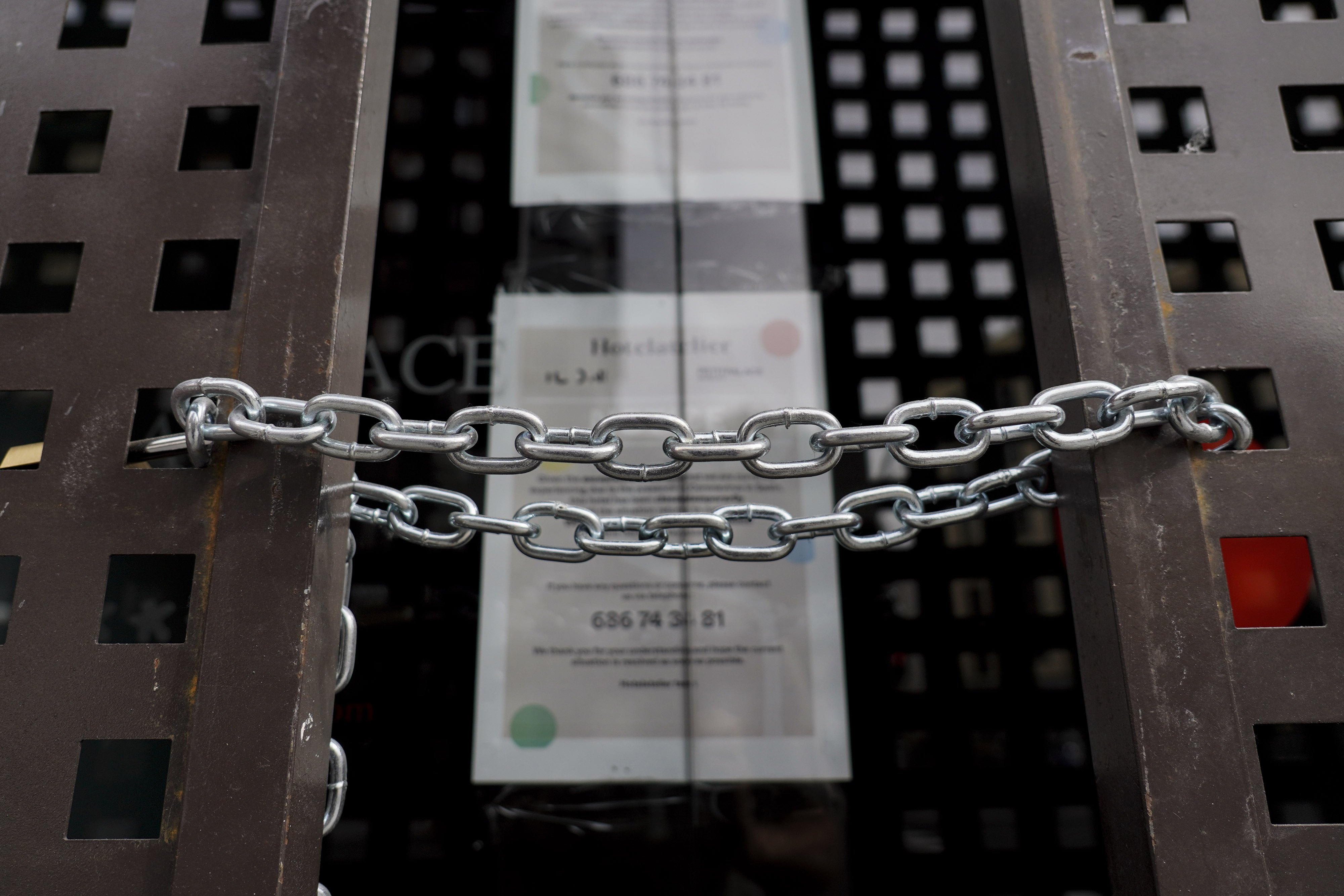 A chain secures locked gates in front of a shuttered store in Madrid.