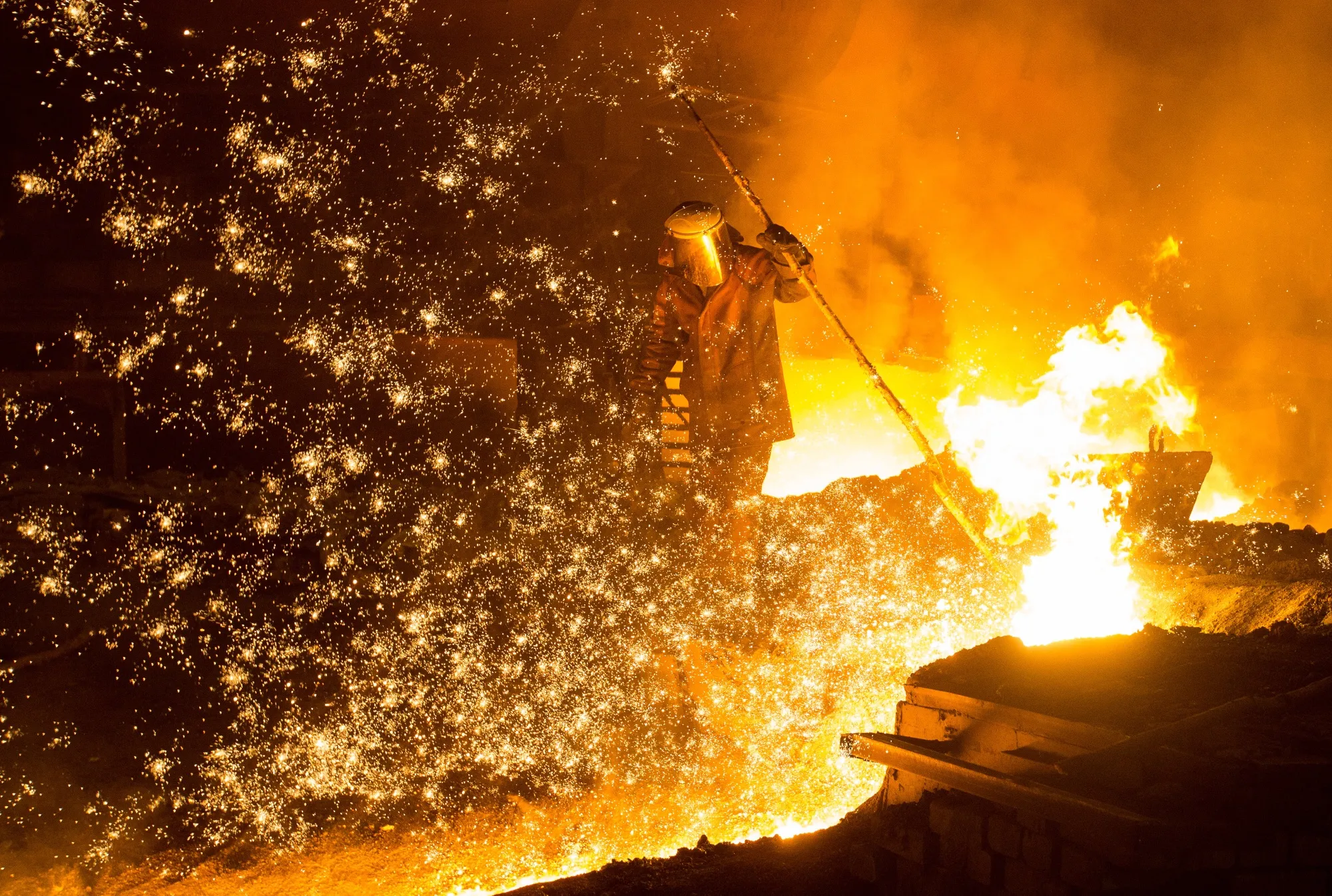 A worker supervises the flow of hot liquid metal as it flows from the blast furnace at the Evraz Consolidated West-Siberian Metallurgical Plant in Novokuznetsk, Russia.