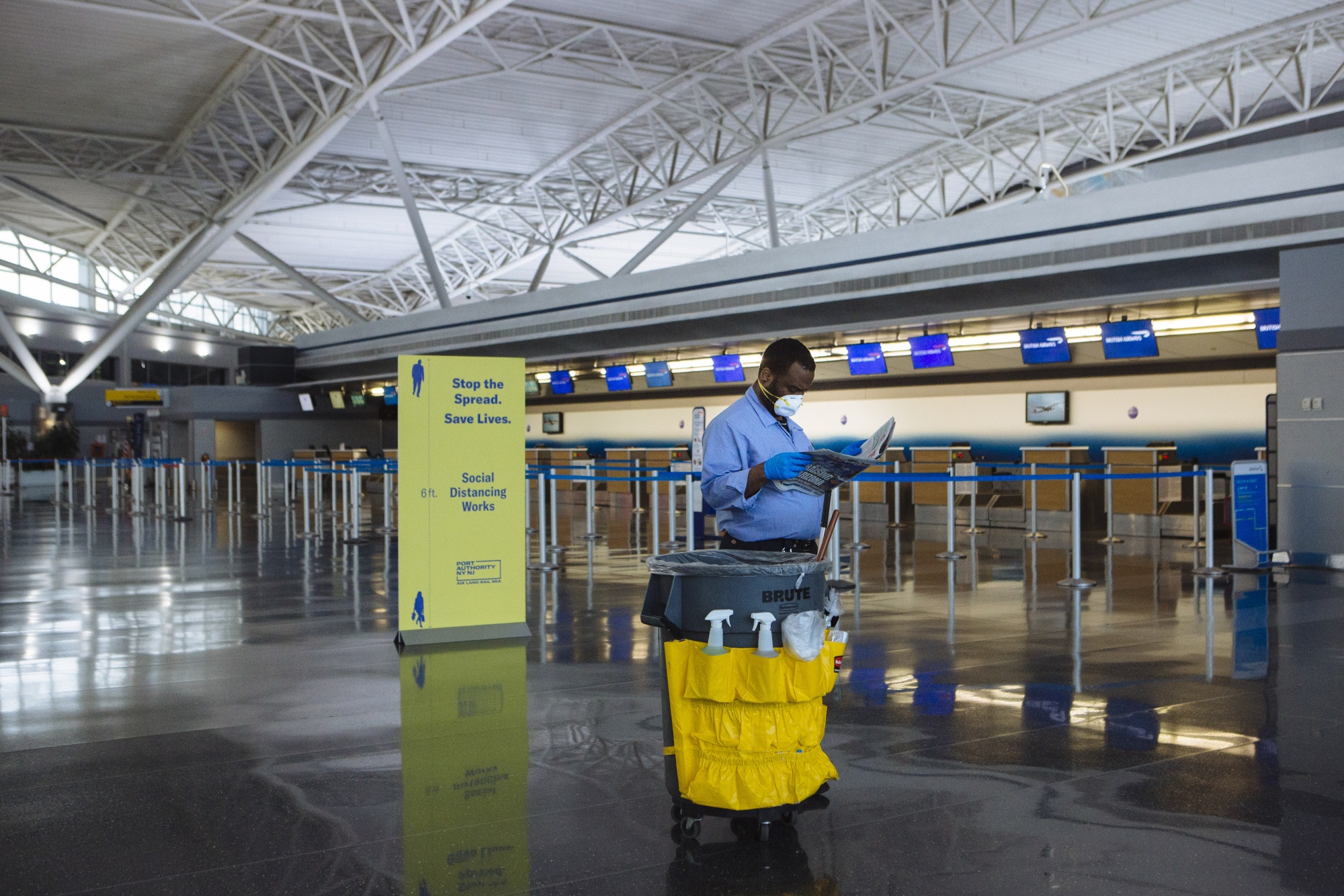 A worker wearing a protective mask reads in Terminal 8 at John F. Kennedy International Airport in New York on April 9.