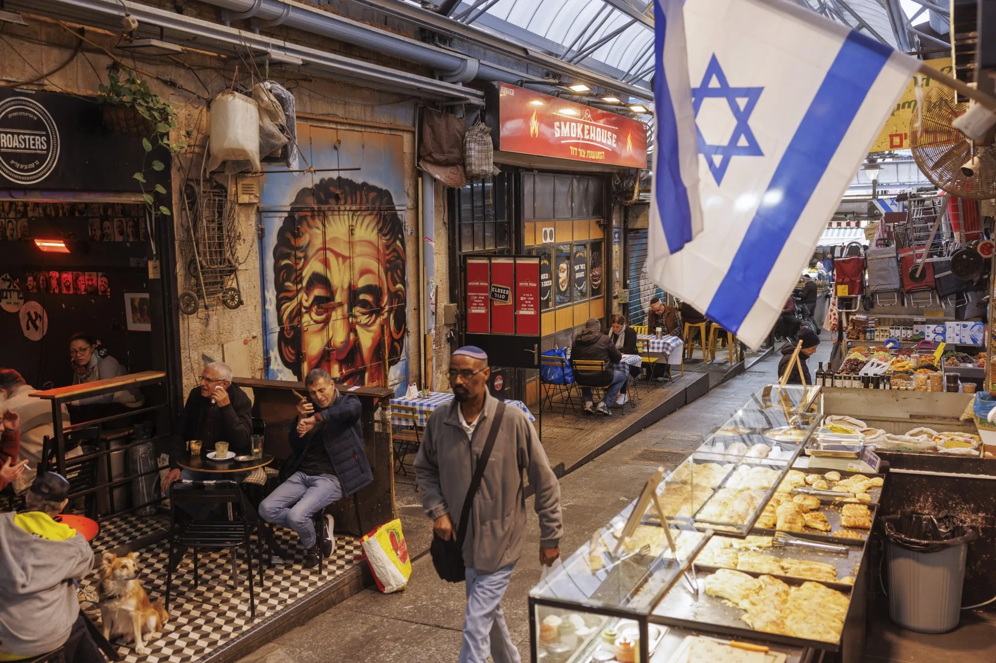 A shopper passes an Israeli national flag at the Machane Yehuda market in Jerusalem, Israel.