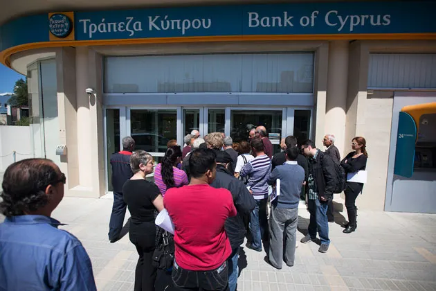 Customers queue outside a Bank of Cyprus branch in Nicosia ahead of its opening for the first time in two weeks on March 28