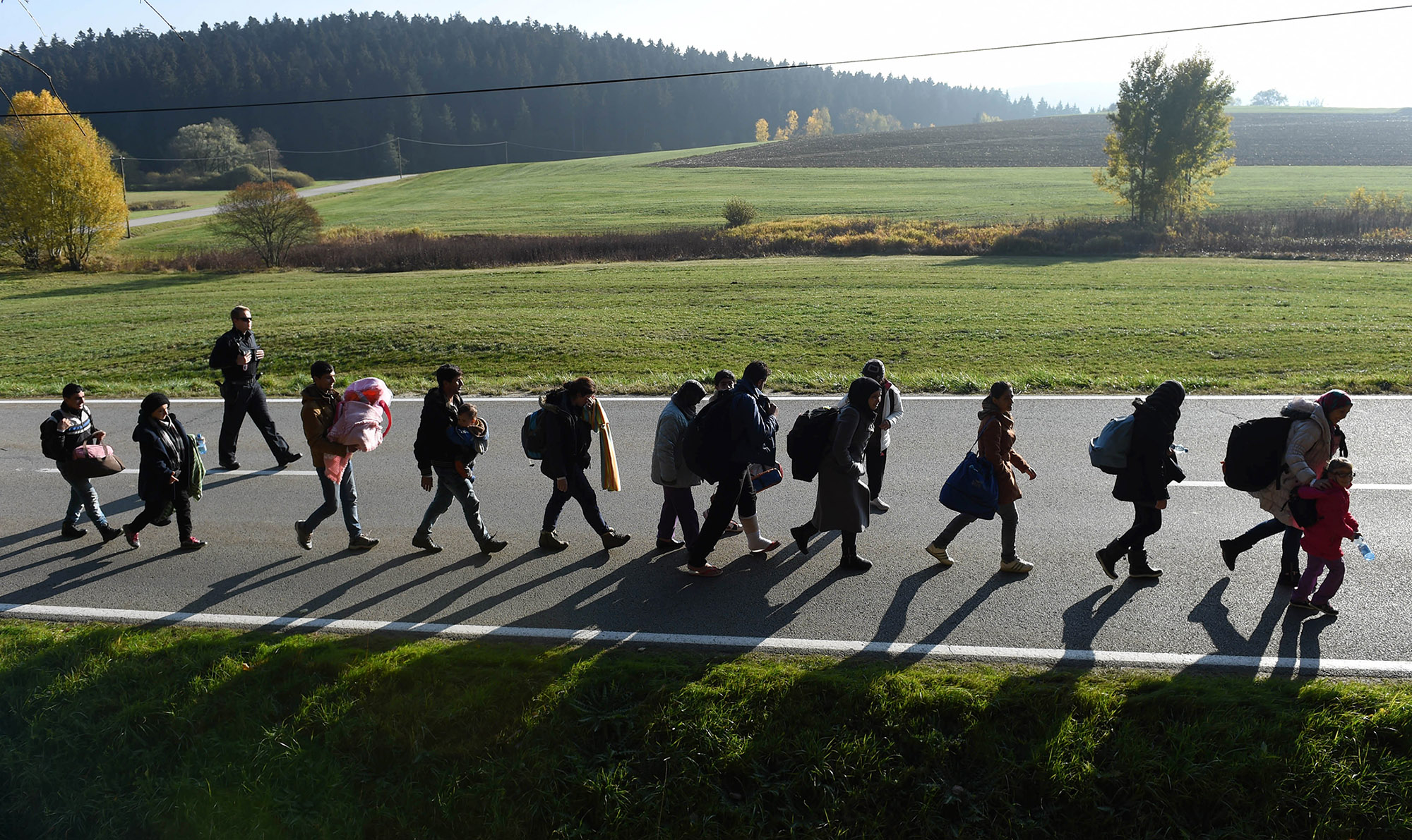 Migrants walk on the road after crossing the Austrian-German border near the Bavarian village Wegscheid, southern Germany, on Oct. 30, 2015.
