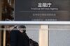 Two pedestrains walk past the Financial Services Agency (FSA) headquarters in Tokyo, Japan, on Tuesday, Feb. 13, 2018. Cryptocurrency exchange Coincheck inc., which lost about $500 million to hackers last month, faced a deadline Tuesday to explain how the hack occurred and plans for improving its security to regulators at Japan's FSA.