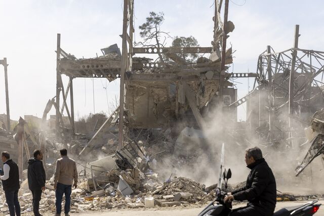 Workers and media stand near the site of a Tehran police facility struck during the initial US-Israel attack on Iran.