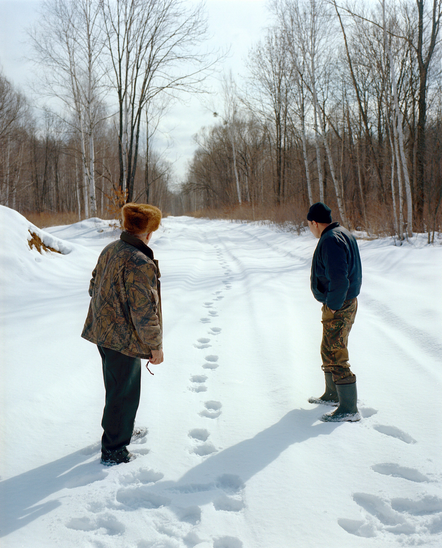 Batalov and his son inspecting&nbsp;tiger paw prints in the snow.