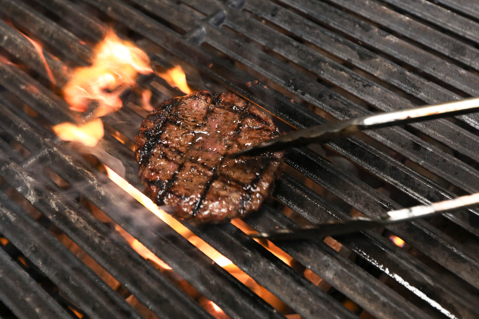 A chef cooks a burger on a grill