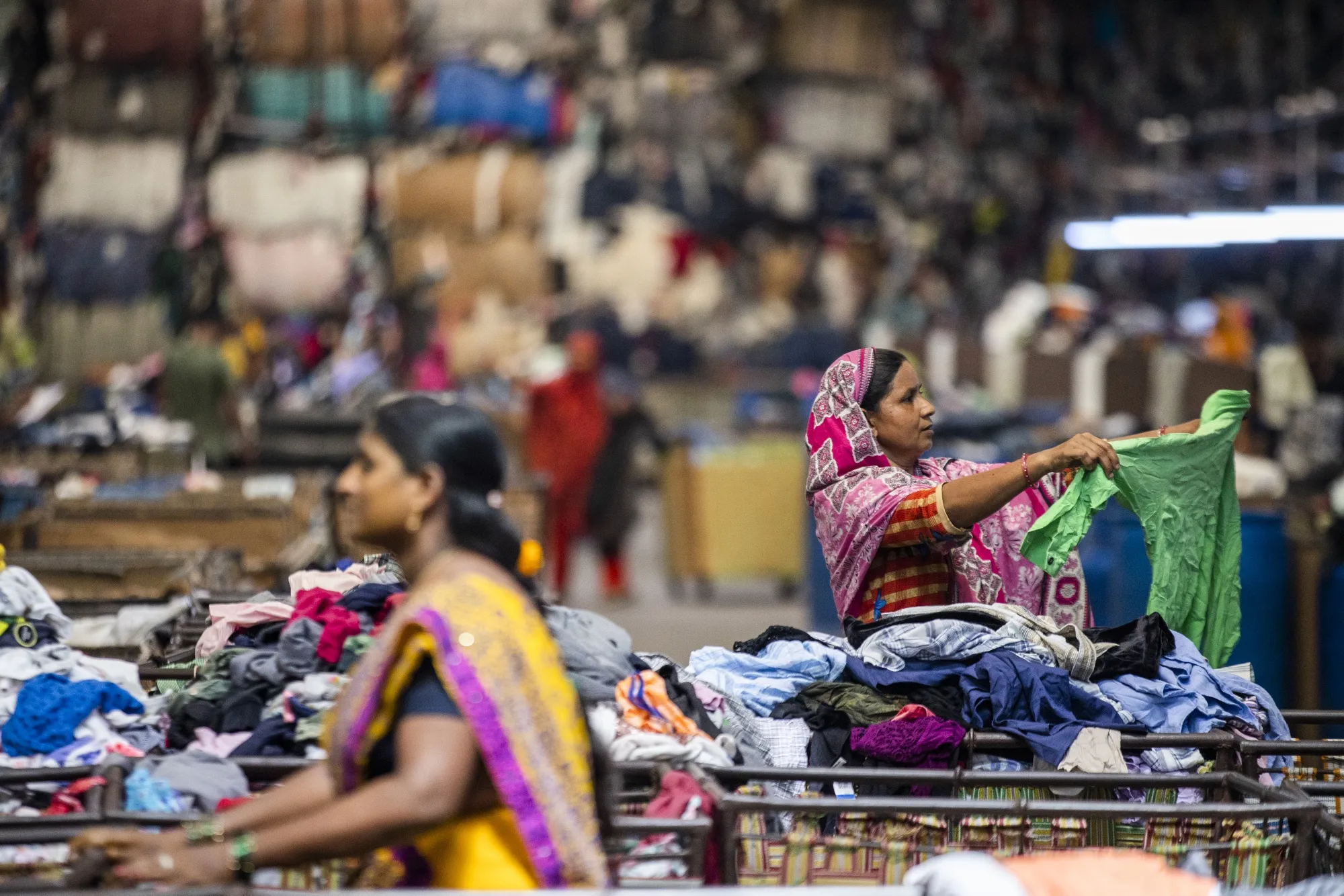 Workers sift through piles of clothes at the grading area of a factory floor&nbsp;in Kandla, India.
