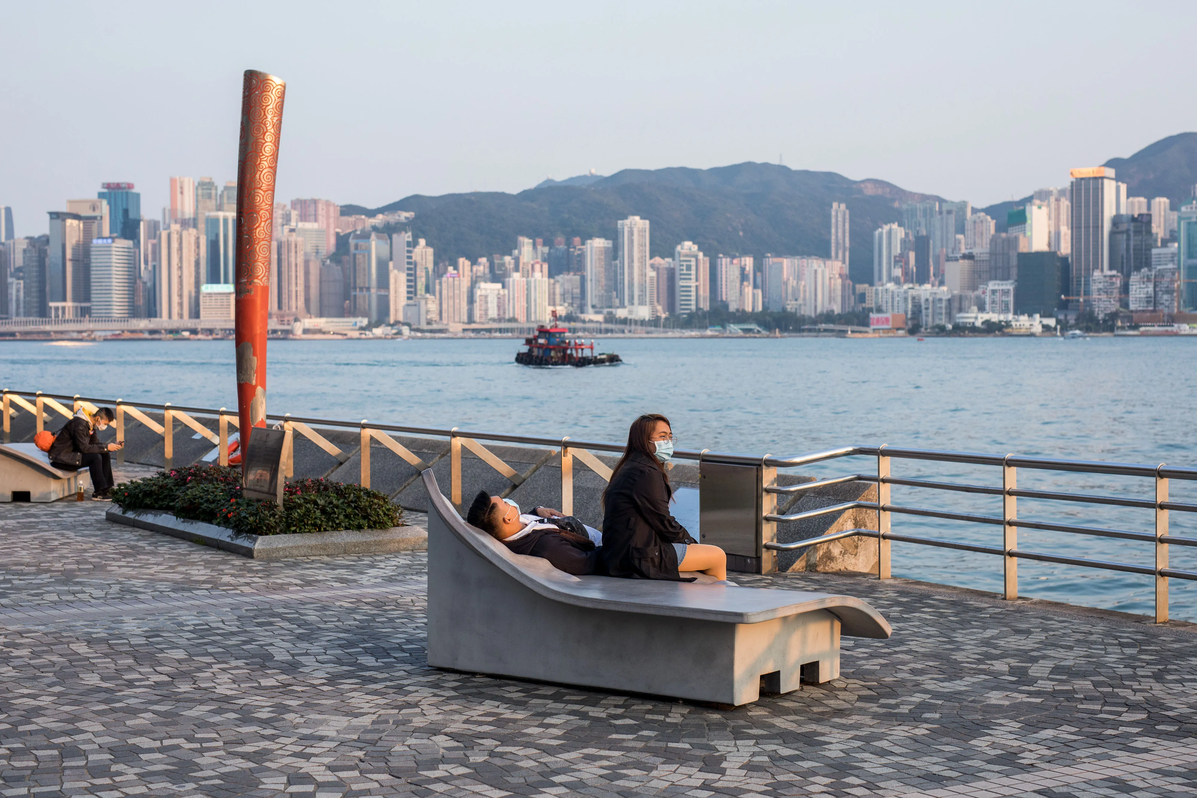 Visitors sit on the waterfront at Victoria Harbour in the Tsim She Tsui district in Hong Kong on Jan. 29.