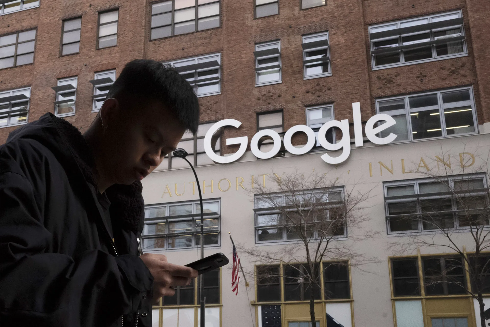 A man using a mobile phone walks past Google offices in New York.