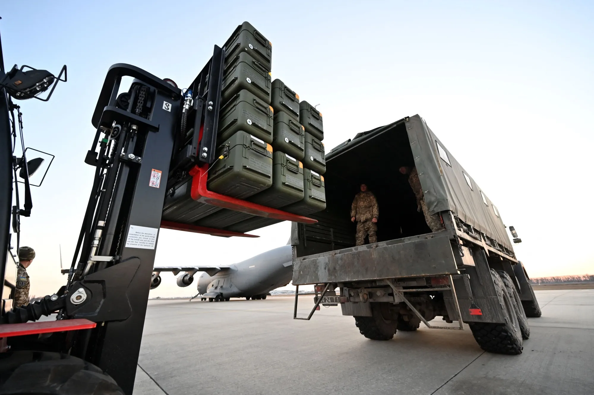 Servicemen load&nbsp;military equipment into a truck.