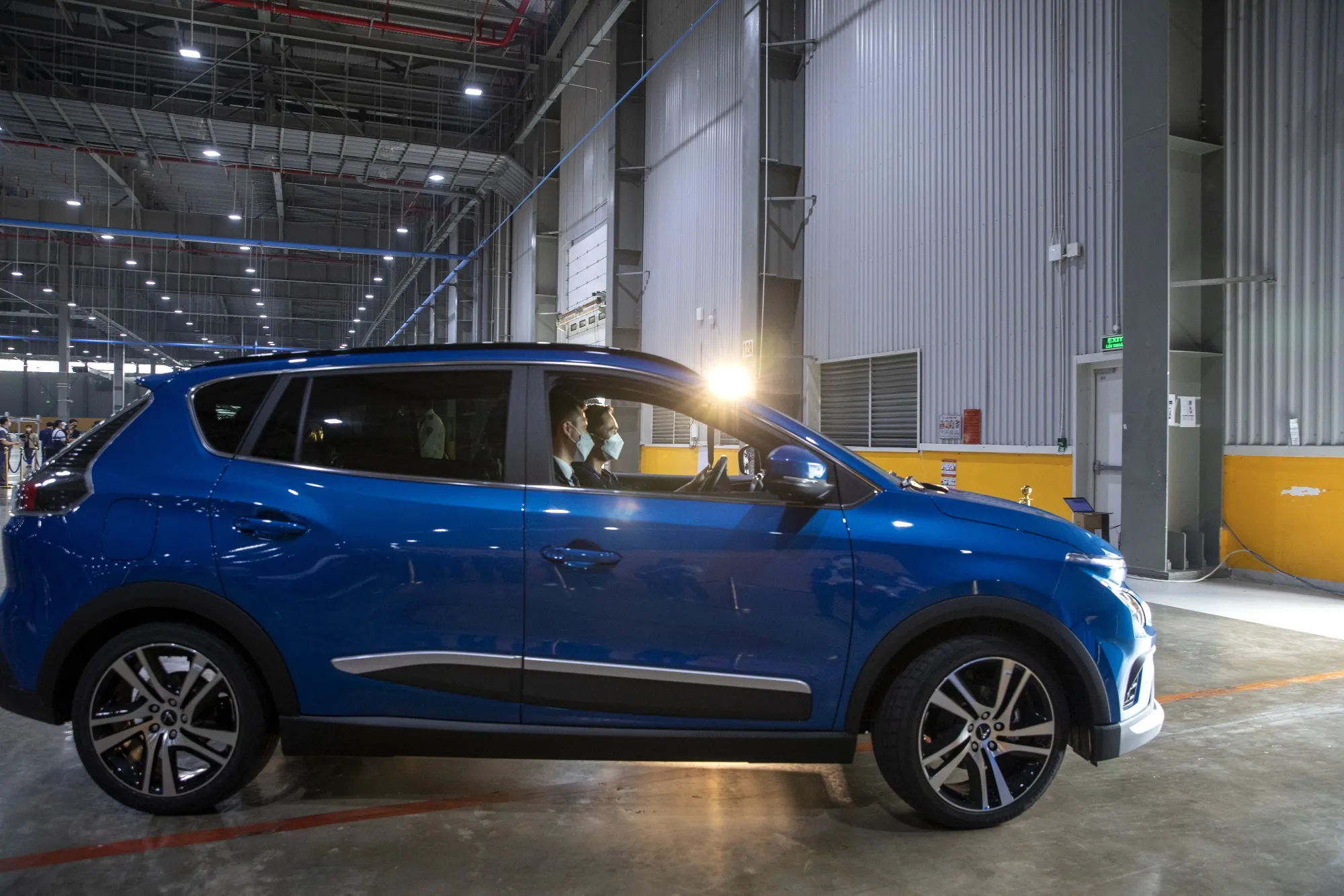 Customers drive their VinFast VF e34 electric SUV out of the garage at the automaker’s factory.