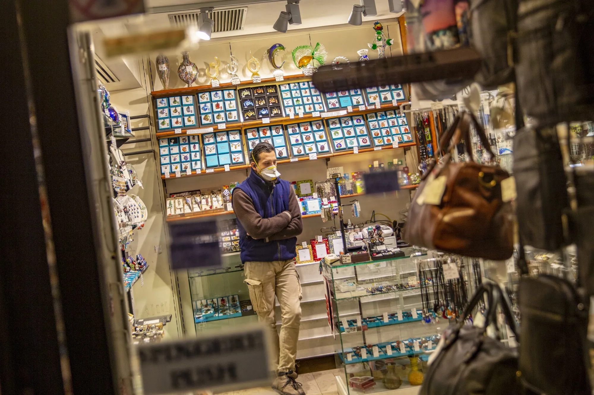 A worker, wearing a protective face mask, stands at his souvenir shop in Venice.
