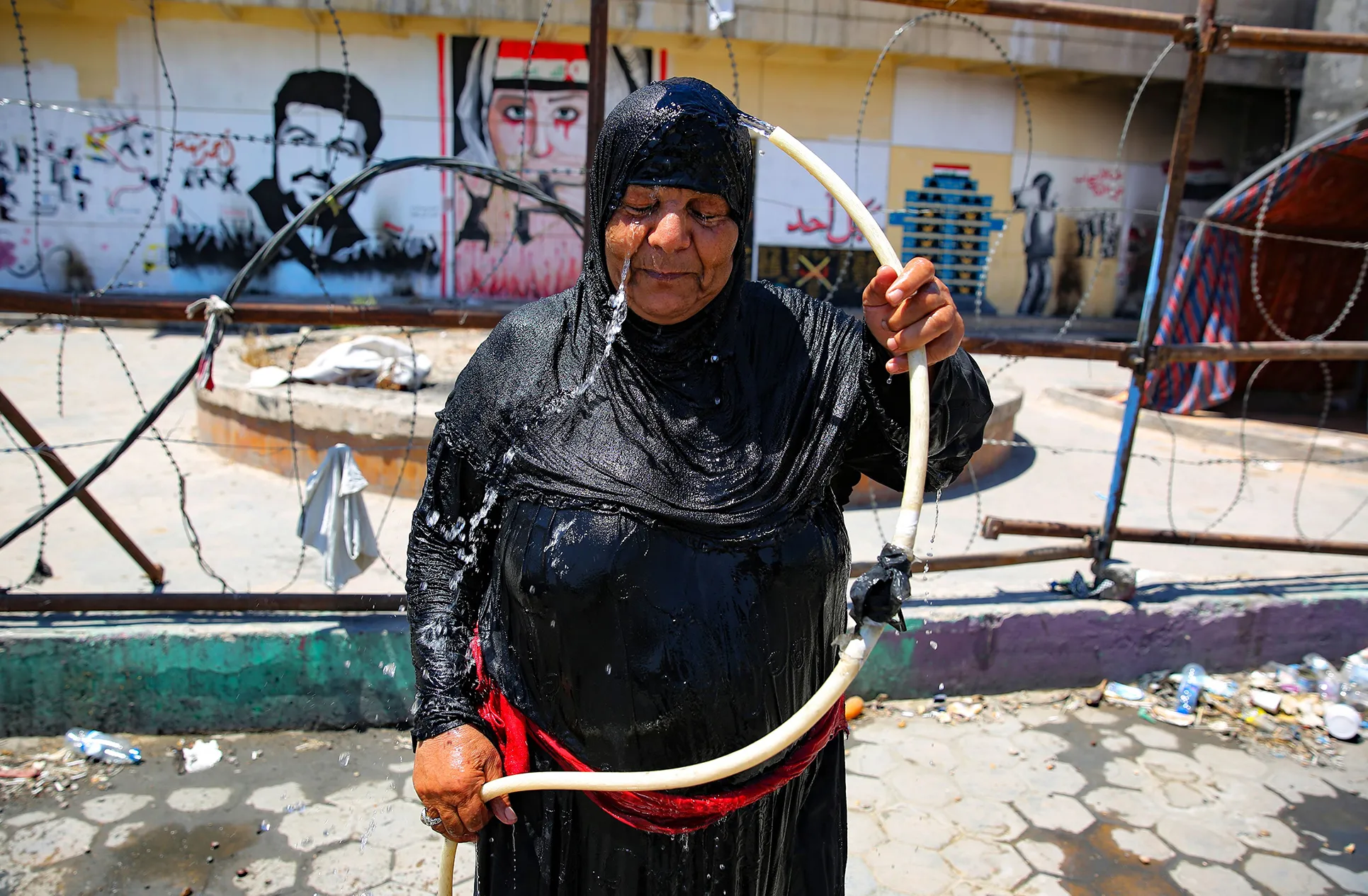An Iraqi woman cools down with water from a hose in Baghdad, on Aug. 1.