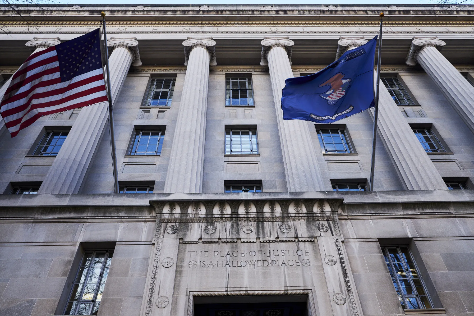 The American and U.S. Department of Justice (DOJ) flags fly outside the DOJ headquarters in Washington, D.C., U.S.