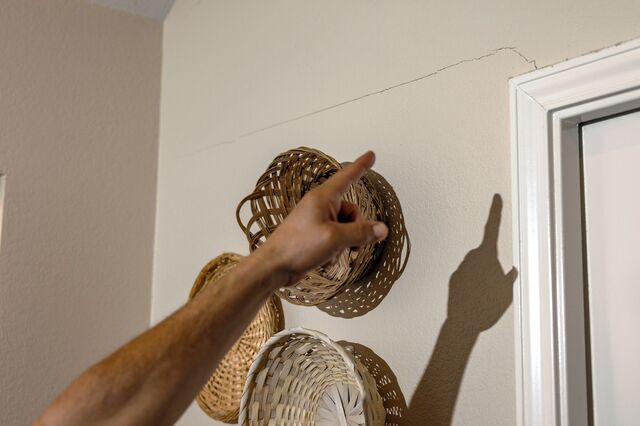 A person points to a crack in a wall at Pam Alvarado's home.