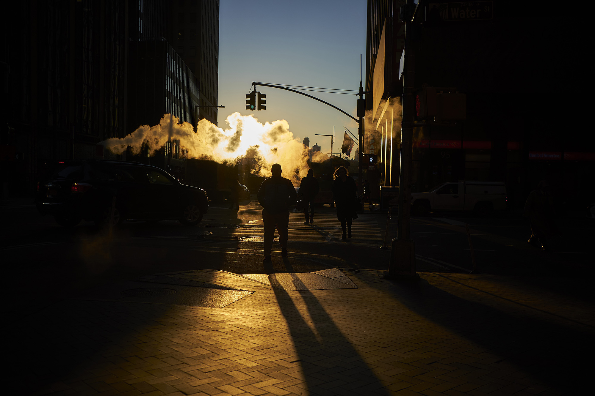 Steam rises as pedestrians cross a street near the New York Stock Exchange.
